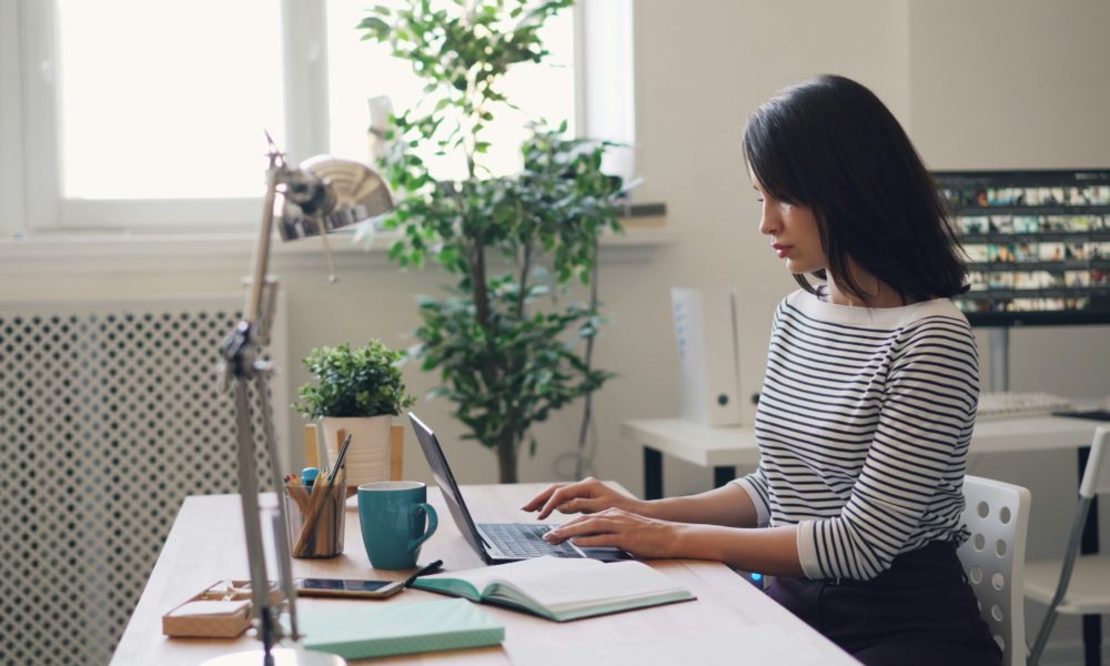 une femme assise à un bureau à l’aide d’un ordinateur portable